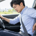 車の運転中に腰の痛みを感じる男性